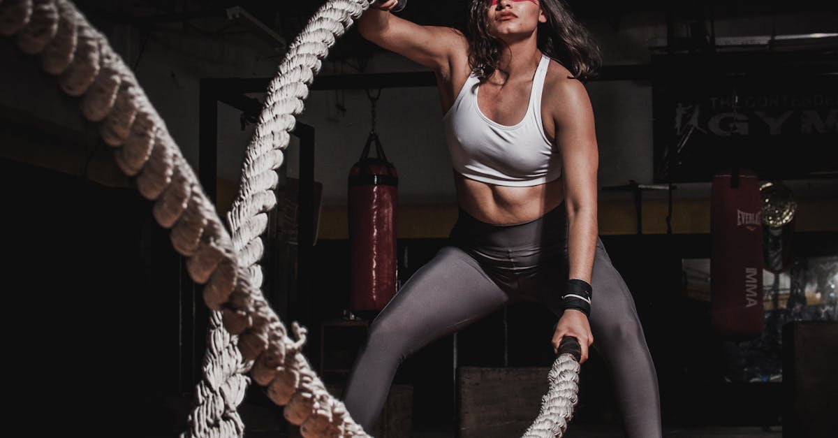 Female athlete demonstrating strength with battle ropes in a gym.