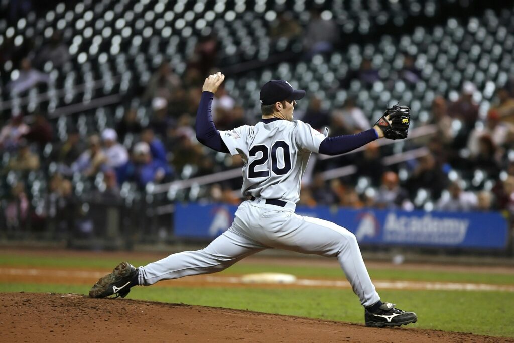 Baseball player pitching on field during a game, showcasing athletic action and focus. Ballistic training exercises, chiropractic exercise coach.