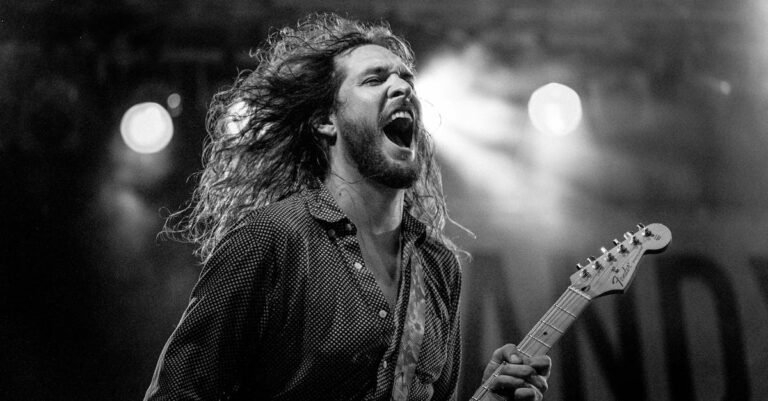 Expressive guitarist passionately performing live on stage in black and white. musician injuries, musician chiropractor
