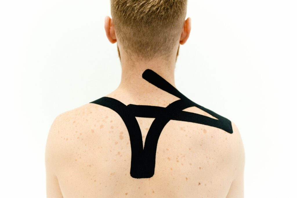 Black kinesio tape applied to man's back for therapeutic treatment on a white background.