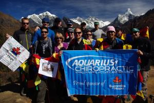 Summits of Hope climbers successfully completing Kilimanjaro and holding Aquarius Chiropractic banner.